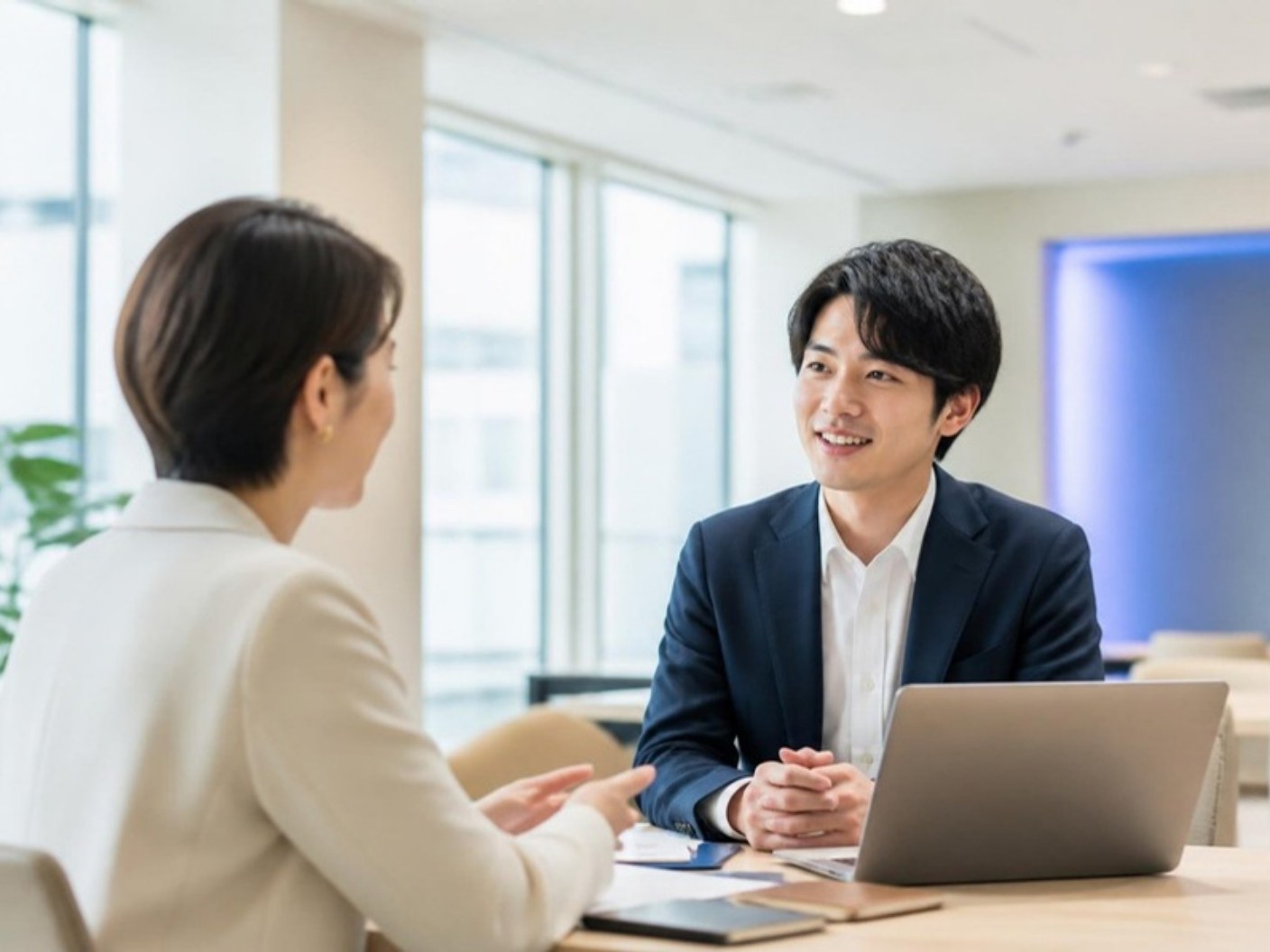 明るいオフィスで、担当者と若い求職者が机をはさんで話している面談の様子（イメージ）